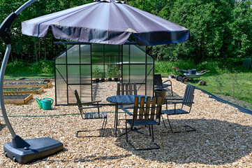 Obraz premium greenhouse table and chairs with sunshade in garden