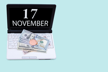 Fototapeta na wymiar Laptop with the date of 17 november and cryptocurrency Bitcoin, dollars on a blue background. Buy or sell cryptocurrency. Stock market concept.