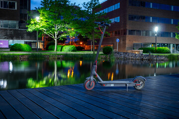 Electric scooter on a wooden pier by the water at night.