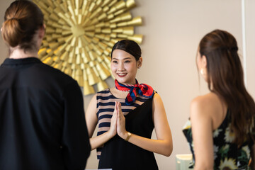 beautiful young asian woman receptionists working at a reception desk make pay respect (sawasdee) to customer.