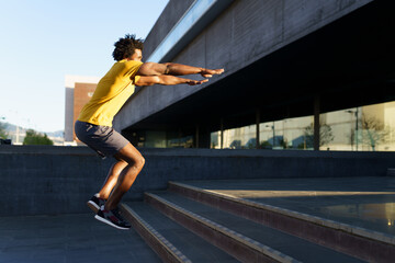 Black man doing squats with jumping on a step.