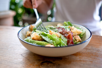 Closeup image of a woman eating a Caesar salad