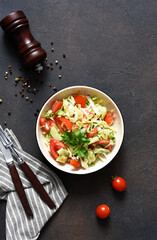 Classic vegetable salad. Salad with cabbage, cucumbers and tomatoes with lemon juice on a concrete background. View from above.