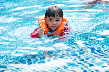 Fototapeta na wymiar Happy Asian family vacation. Young Asian father with son and daughter enjoy by swimming pool at the hotel. Happy family summer vacation concept.