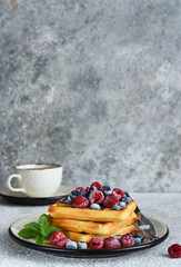 Vanilla Belgian waffles with berries and a cup of coffee for breakfast.