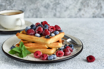 Vanilla Belgian waffles with berries and a cup of coffee for breakfast.