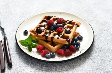 Vanilla Belgian waffles with berries and a cup of coffee for breakfast.