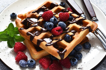 Vanilla Belgian waffles with berries and a cup of coffee for breakfast.