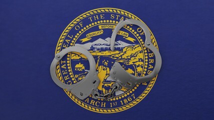 A half opened steel handcuff in center on top of the US state flag of Nebraska
