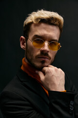 blond man with glasses and black jacket orange sweater portrait 