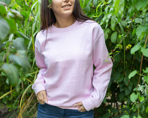 Front view of unrecognizable woman wearing pink sweatshirt outside. There is copy space on blose for inscription, design or logo. It's could be used for breast cancer awarness campaign.