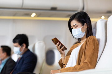 Young asian woman wearing face mask prevent covid-19 virus sitting comfortable business class seat.
