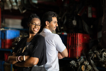 African American female worker and man customer choose and inspecting car part products while working in a old car part warehouse store.