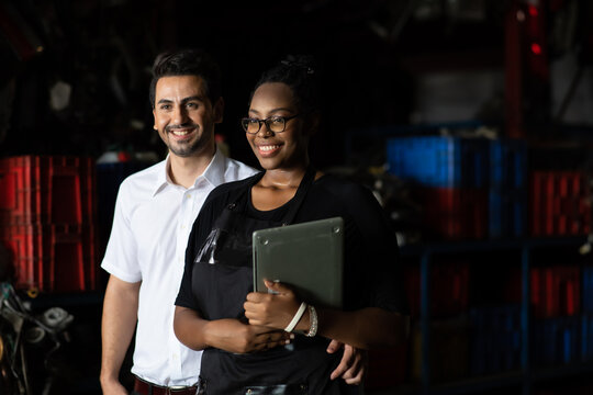 African American female worker and man customer choose and inspecting car part products while working in a old car part warehouse store. - Powered by Adobe