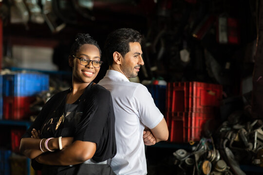 African American female worker and man customer choose and inspecting car part products while working in a old car part warehouse store.
