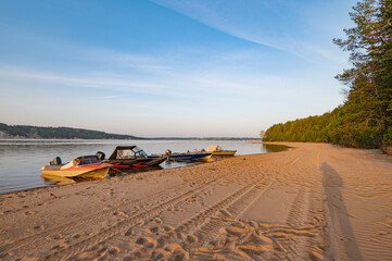 Fototapeta na wymiar Morning landscape, sunrise over the river, sandy beach near the shore are boats.