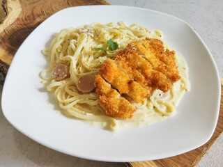 Fettucine white cream sauce with chicken katsu in white plate - Italian food style. Selective Focus
