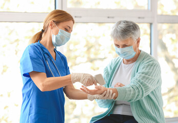 Obraz premium Doctor measuring temperature of senior woman in clinic