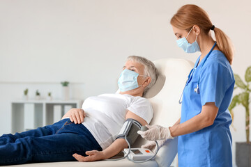 Obraz premium Doctor measuring blood pressure of senior woman in clinic