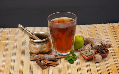 Closeup shot of an old bronze pounder and herbal tea with ingredients on a wooden mat
