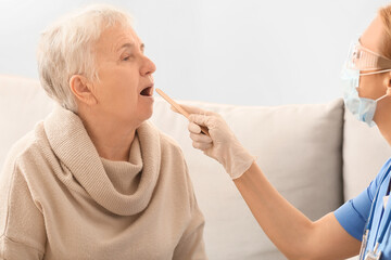 Doctor examining senior woman at home