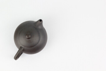 A Chinese black ceramic teapot and teacup isolated on a white background.