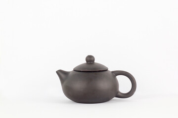 A Chinese black ceramic teapot and teacup isolated on a white background.