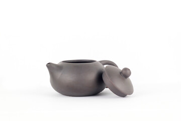 A Chinese black ceramic teapot and teacup isolated on a white background.
