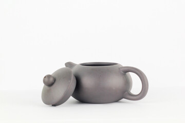 A Chinese black ceramic teapot and teacup isolated on a white background.
