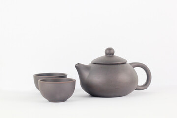 A Chinese black ceramic teapot and teacup isolated on a white background.