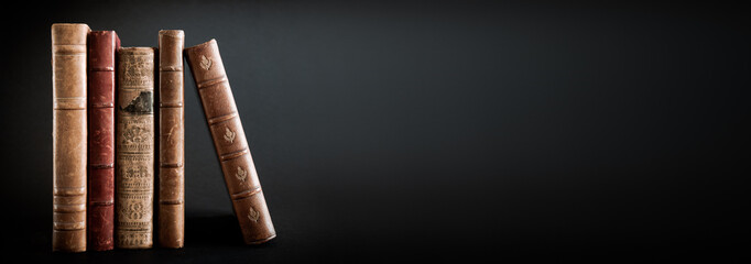 Row of old books on black background banner