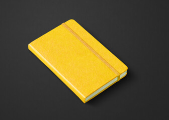 Yellow closed notebook isolated on black