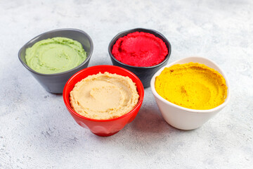 Traditional Middle eastern food various hummus. Green,yellow,beet and traditional hummus in small bowls.