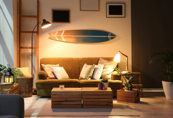 Interior of modern stylish room with surfboard and sofa in evening