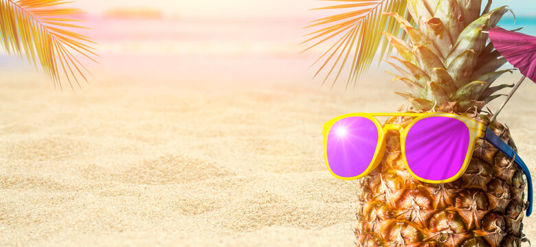 Summer tropical pineapple background. Pineapple in sunglasses under a palm tree on a beach background. Cocktail party on the beach, rest, relaxation and summer concept