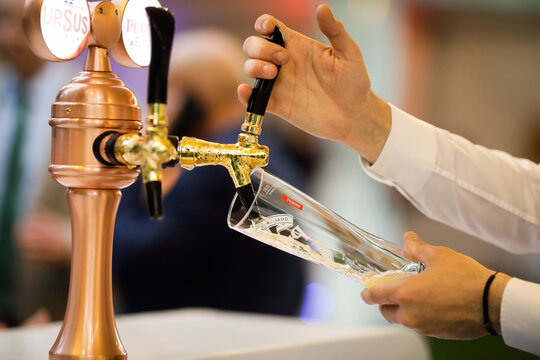 Shallow depth of field (selective focus) details with a man pouring Peroni beer into a glass at a bar.