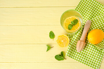 Glass of healthy lemonade and squeezer on color wooden background