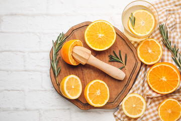 Glass of healthy lemonade, citrus fruits and squeezer on brick background