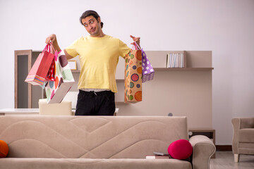 Young man with many bags in Christmas concept at home