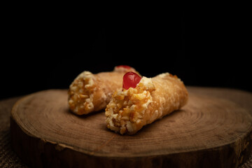 Close-up of two cannoli on wooden slice and burlap cloth.