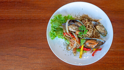 Top view of Spaghetti with Spicy Mix seafood in white plate on the wooden background with copy space.