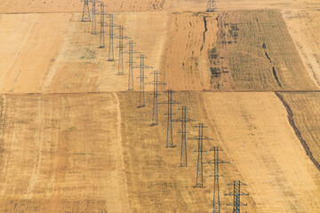 Power transmission towers in the yellow farm field