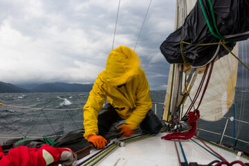 Motion blur men work with cord of sails of a yacht in the difficult storm sea. Present man's sports it yachting - obrazy, fototapety, plakaty