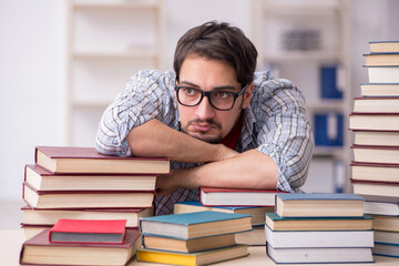 Young male student and too many books in the classroom