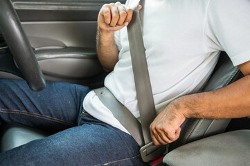 Handsome young asian man  sitting on car seat and fastening seat belt. Car safety concept, insurance concept