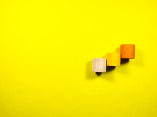 Selective focus. Three colorful wooden block cylinder which are stacked on yellow background with copy and text space.