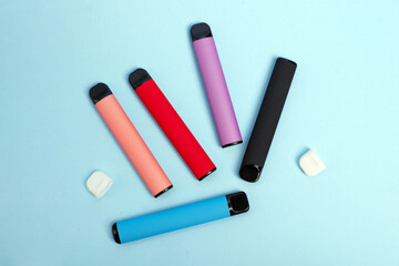 Layout of colorful disposable electronic cigarettes on a blue background. The concept of modern smoking, vaping and nicotine. Top view