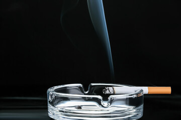 Ash tray with cigarette on dark background