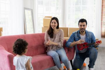 Obraz premium Happy family moment in the house. Father mother and daughter relaxing on red sofa. The family just moving in new house.