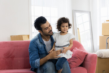 Happy family moment in the house. Father and daughter relaxing on red sofa. The family just moving in new house.